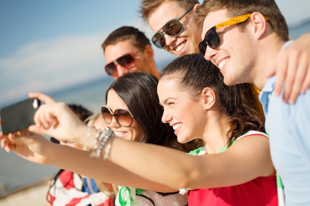 summer, holidays, vacation and happiness concept - group of friends taking picture with smartphone