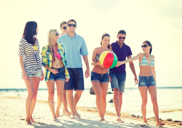 summer, holidays, vacation, happy people concept - group of friends having fun with ball on the beach