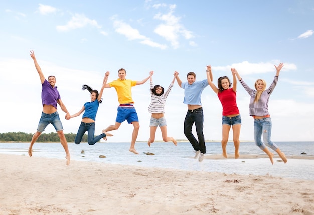 summer, holidays, vacation, happy people concept - group of friends jumping on the beach