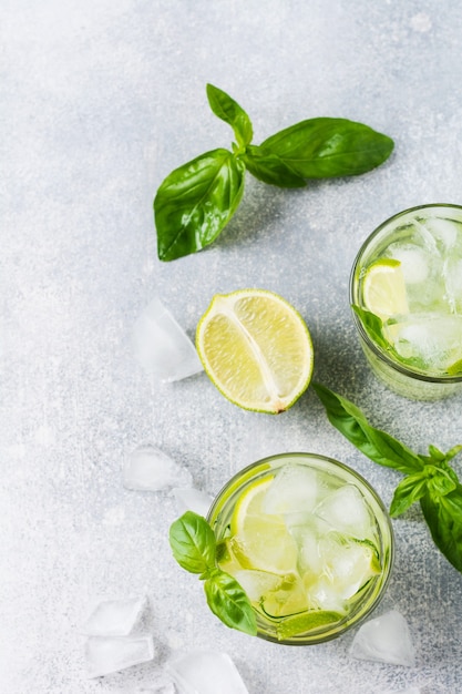 Summer homemade lemonade made from lime, lemon, cucumber and basil with ice in glass on an old concrete. 