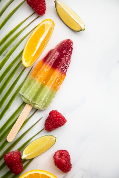 Summer ice lollies with fruit and a tropical palm leaf