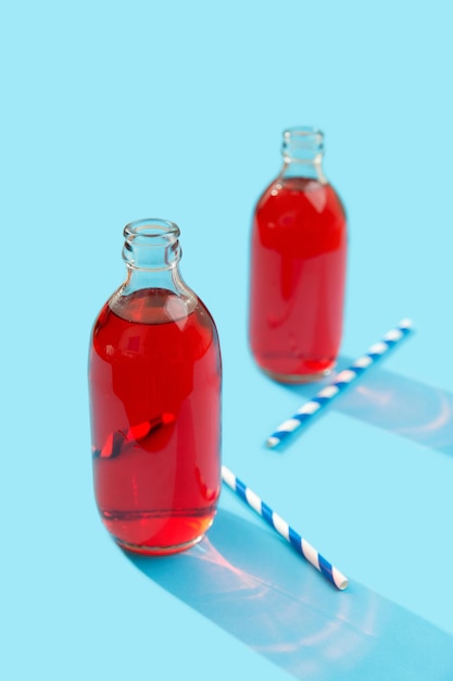 Summer iced cranberrie punch cocktail in bottle on blue background