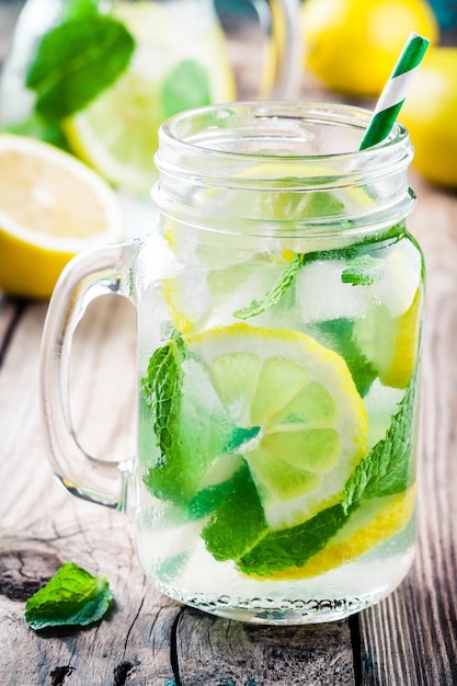 Summer iced drink with lemon and mint on wooden rustic table