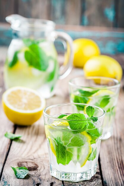 Summer iced drink with lemon and mint on wooden rustic table