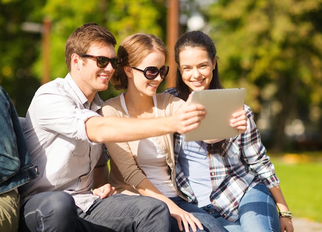 summer, internet, social networking and teenage concept - group of teenagers taking photo with tablet pc outside