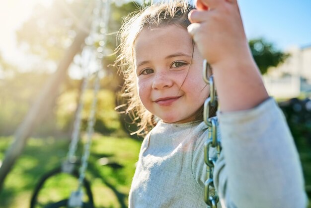 Summer is in full swing Portrait of a cute little girl sitting on a swing in a park