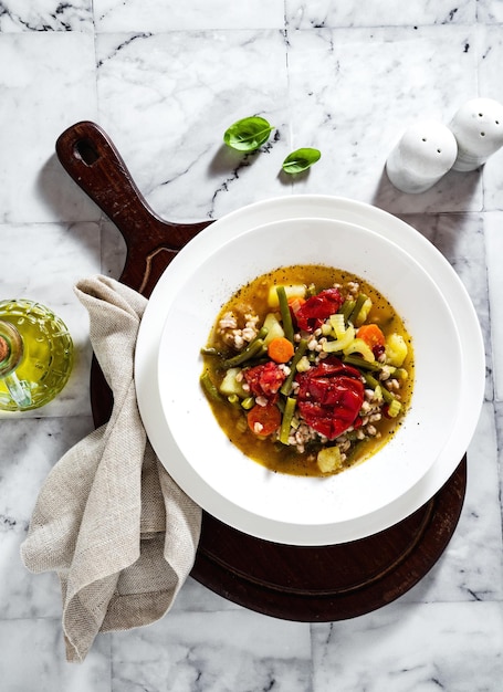 Foto zuppa di minestrone estivo italiano con pomodori e pane fatto in casa su un tavolo di marmo