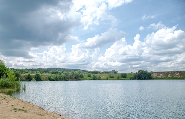 Summer landscape in the countryside with river, forest and clouds.
