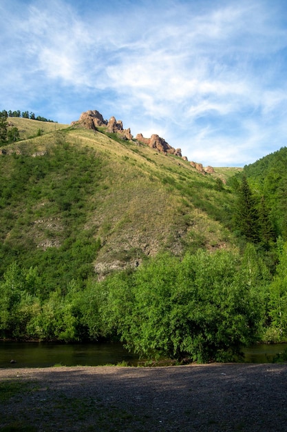 Paesaggio estivo montagne rocce e un fiume contro un cielo blu con nuvole con spazio di copia turismo ricreativo attivo