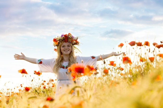 Summer landscape, poppies in the wheat field. Rural view and pretty woman with raised hands