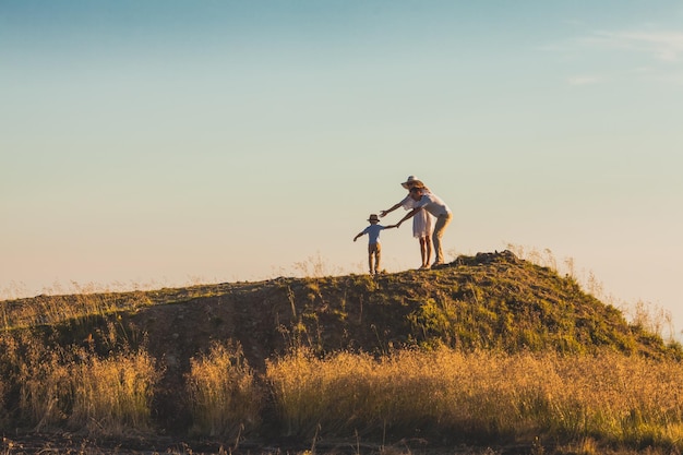 Summer landscape with parents and little son Preschool boy trying to break free from his parents Conflicts between parents and children Parents trying to stop their son from escaping