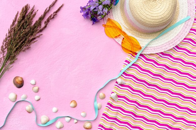 Summer leisure accessories on a pink background with shells.