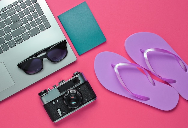 Summer leisure. Summertime relax.Laptop and beach accessories on pink background. Studio short. Beach object. Top view. Flat lay