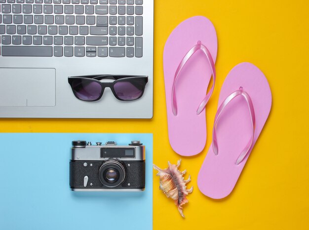 Summer leisure. Summertime relax. Laptop and travel accessories on yellow background. Studio short. Beach object.