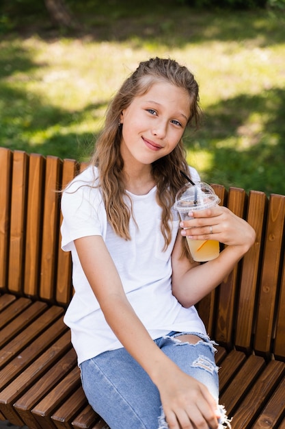 Photo summer lemonade cocktail outdoor happy girl holding cup with orange lemonade and smiling and laughing