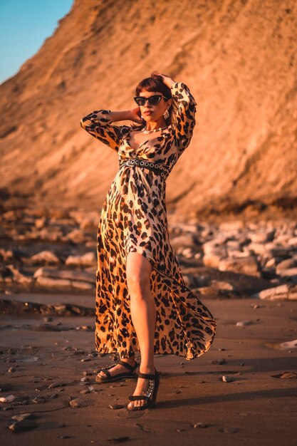 Summer lifestyle on a beach next to rocks of a young brunette Caucasian woman