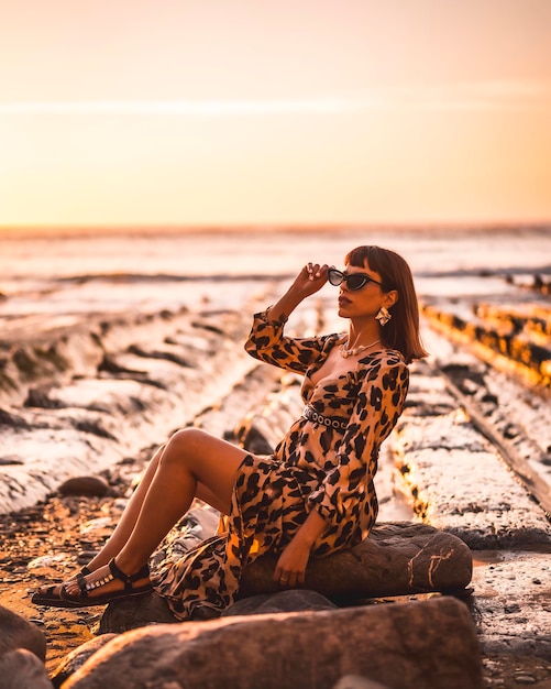 Summer lifestyle on a beach next to rocks of a young brunette Caucasian woman