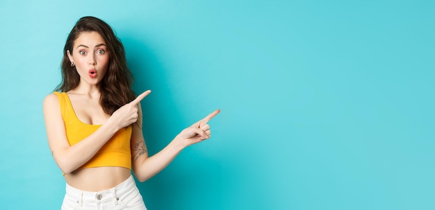 Photo summer lifestyle concept surprised stylish woman showing direction pointing fingers right that way gesture standing over blue background