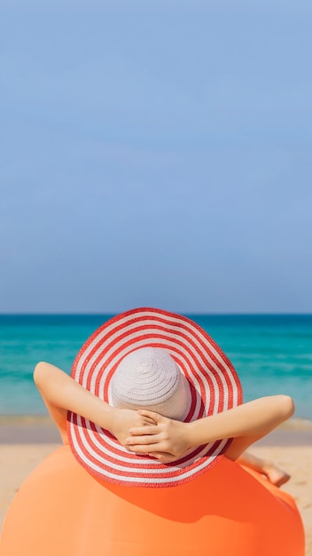 해변에 있는 주황색 소파에 앉아 있는 예쁜 여자의 여름 라이프스타일 초상화