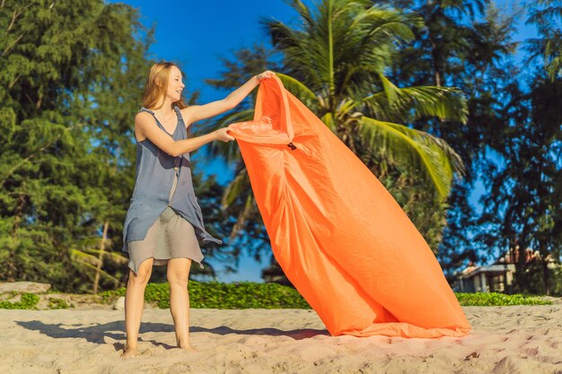 여성의 여름 라이프스타일 초상화는 열대 섬 해변에서 풍선 오렌지 소파를 부풀려 공기 침대에서 휴식을 취하고 삶을 즐깁니다.