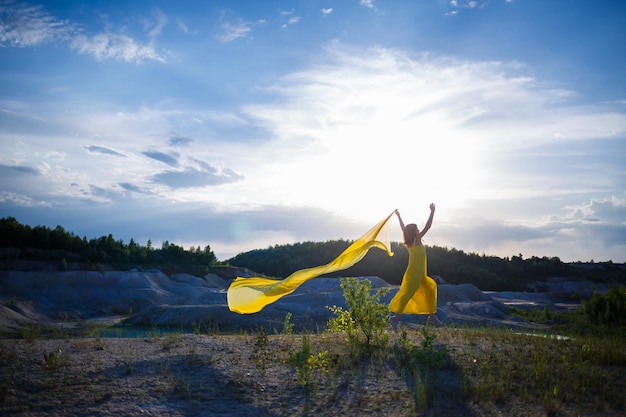 Summer lifestyle of stunning happy woman running in nature. In a long yellow dress. Romantic mood. Enjoying the sunshine. Sunny day. Selective focus