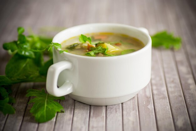 Summer light soup with oatmeal and arugula in a plate