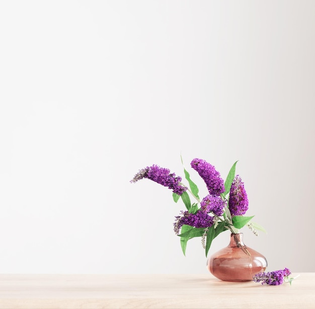 Summer lilac in glass vase on wooden shelf