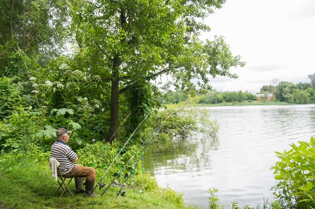 In summer a man sits near the river and catches fish