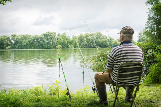 Летом мужчина сидит у реки и ловит рыбу