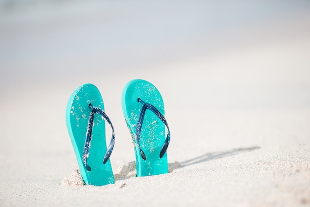 Summer mint flip flops with sunglasses on white beach