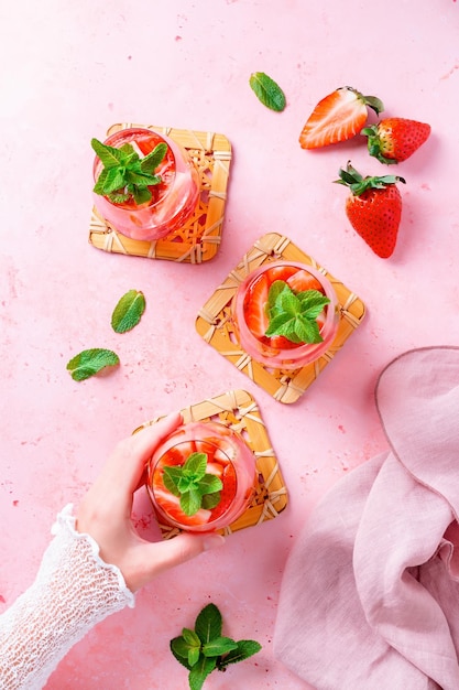 분홍색 탁자 위에 여름 민트와 딸기가 주입된 물