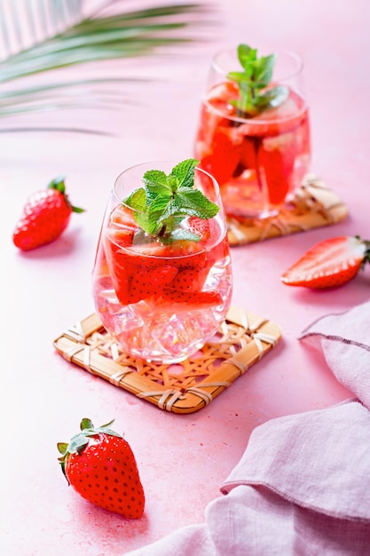 Summer mint and strawberry infused water on pink table top still life top view Summer fruity refreshing cocktail still life closeup