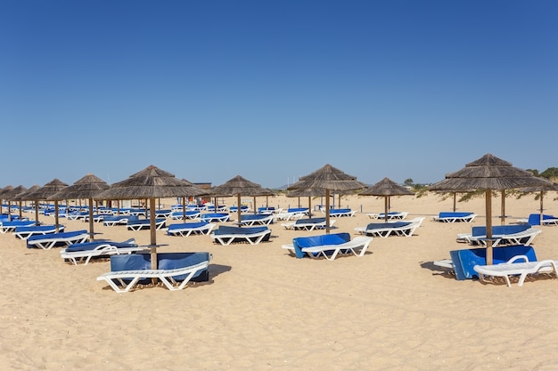 Algarve 해변에서 여름 아침입니다. 모래에 선베드.