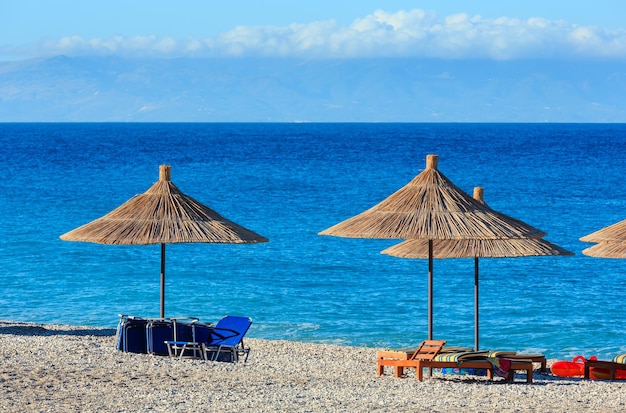 Summer morning pebbly beach with sunbeds and strawy sunshades borsh albania