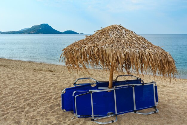 サンベッドと日よけのある夏の朝の砂浜のトリスティニカビーチ（シトニア、ハルキディキ、ギリシャ）。