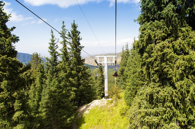 Summer mountain landscape high in the mountains Tall trees of Christmas trees ski lift at the ski base