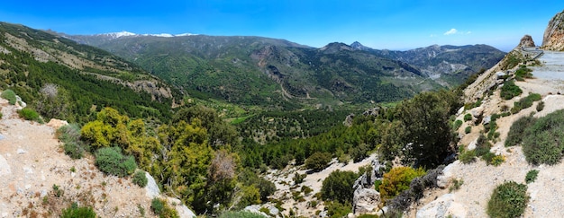 Summer mountain landscape with snow on peak and road (Sierra Nevada National Park, near Granada, Spain). Three shots stitch high-resolution panorama.