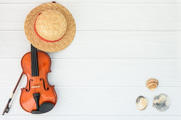夏の音楽休暇の背景あなたのテキストのためのスペースと白い背景の上のバイオリンと麦わら帽子
