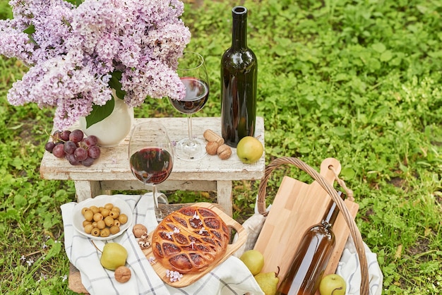 Summer picnic in garden Wine pie fruits and flowers Still life Easter lunch and table