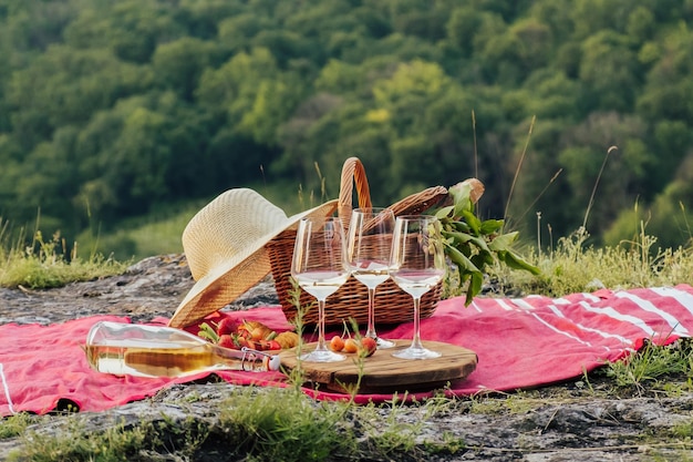 Summer picnic outdoors with wine glasses wine baguette berries and picnic basket