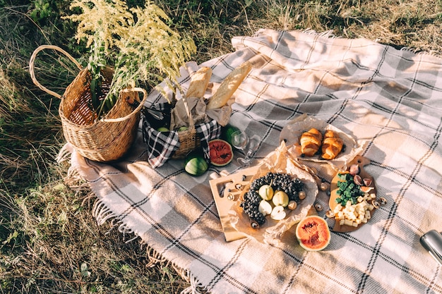 Picnic di estate al tramonto sul tempo soleggiato di stile di vita di concezione del plaid, dell'alimento e della bevanda