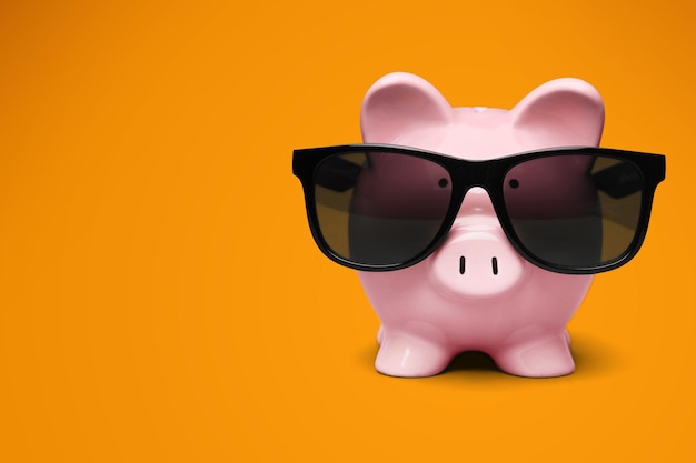 Summer piggy bank with sunglasses on the