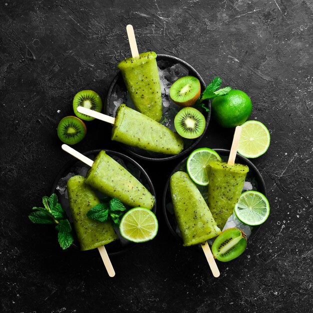 Summer popsicles with lime and kiwi On a black stone background