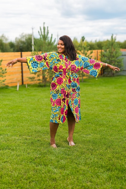 Summer portrait of beautiful african american woman in colourful dress wear standing on backyard Suburban lifestyle and chilling on weekend in countryside and inclusion with diversity concept