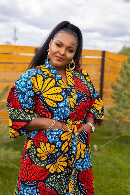 Летний портрет красивой африканской американки в красочной одежде, стоящей на заднем дворе Пригородный образ жизни и отдых на выходных в сельской местности и включение с концепцией разнообразия