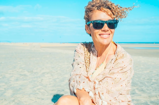Летний портрет веселой счастливой взрослой молодой женщины в солнечных очках, любующейся пляжем.