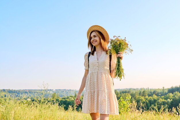 野生の花の花束を持つ幸せな女性の夏の肖像画