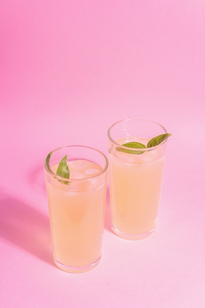 Cocktail rinfrescante estivo. bevanda dolce fredda, luce dura moderna, ombra scura. sfondo rosa pastello