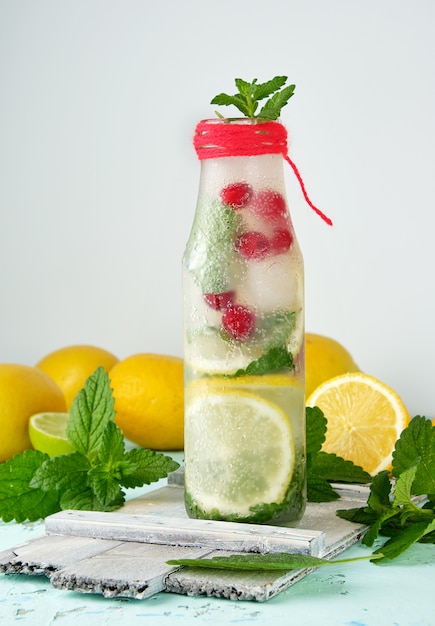 Summer refreshing drink lemonade with lemons, mint leaves, lime in a glass bottle