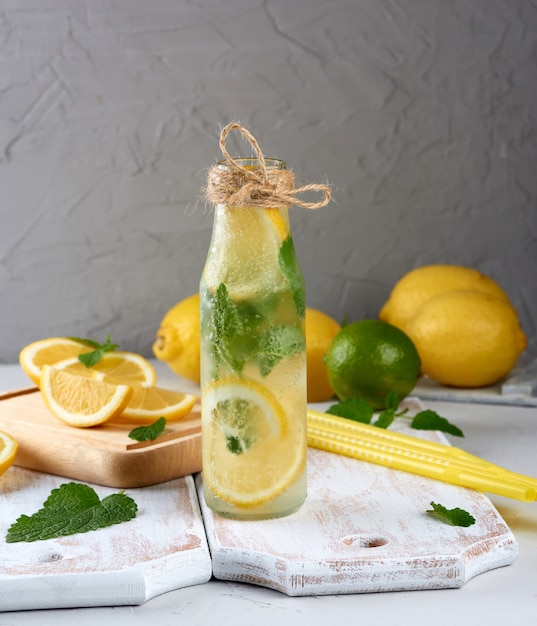 Summer refreshing drink lemonade with lemons, mint leaves, lime in a glass bottle